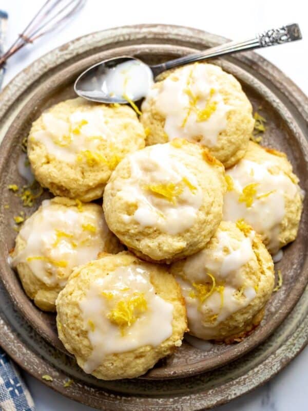 Lemon ricotta cookies on a beige plate with icing on top.