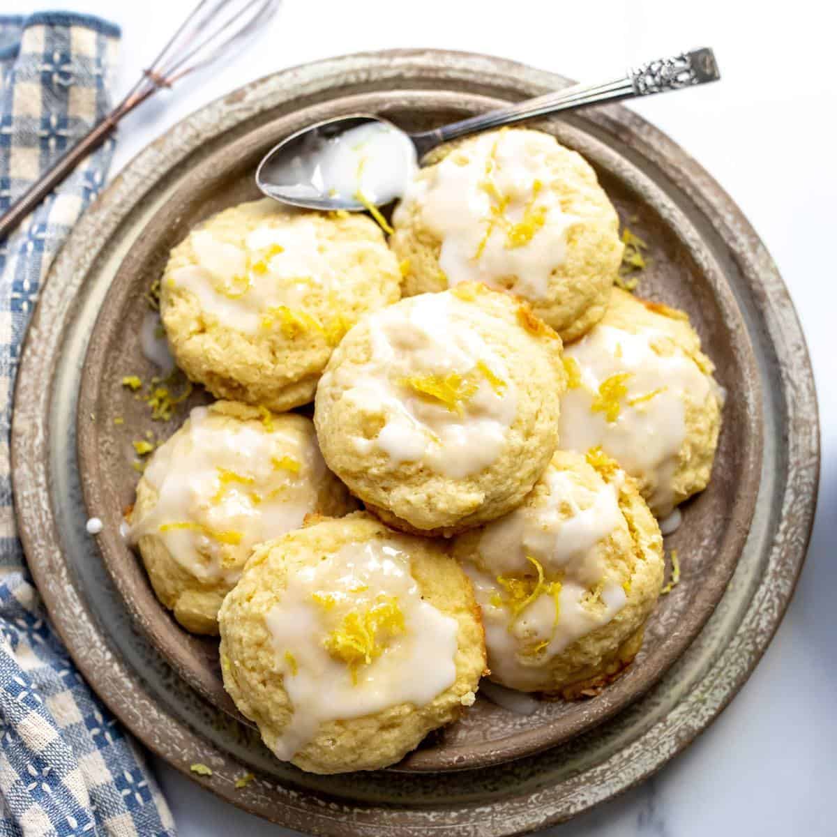 Lemon ricotta cookies on a beige plate with icing on top.