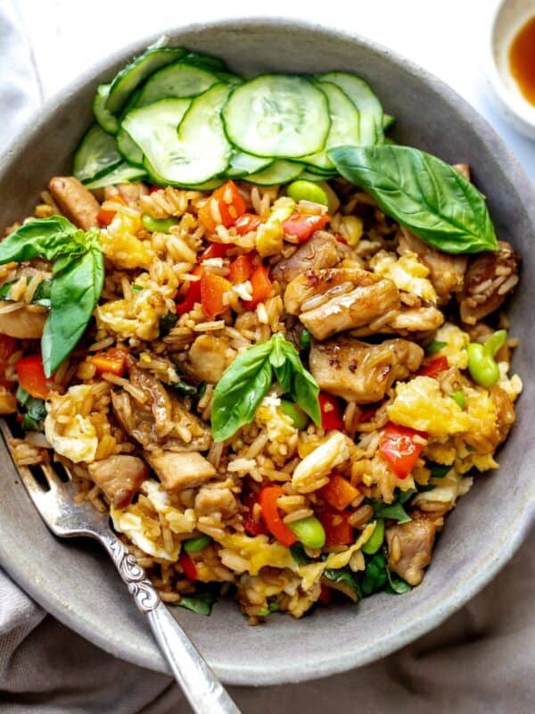 Grey ceramic bowl with Thai Basil Chicken Fried Rice in it and fresh cucumbers to the side.