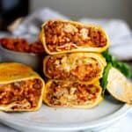 An image of grilled cheese burrito stacked on a plate.