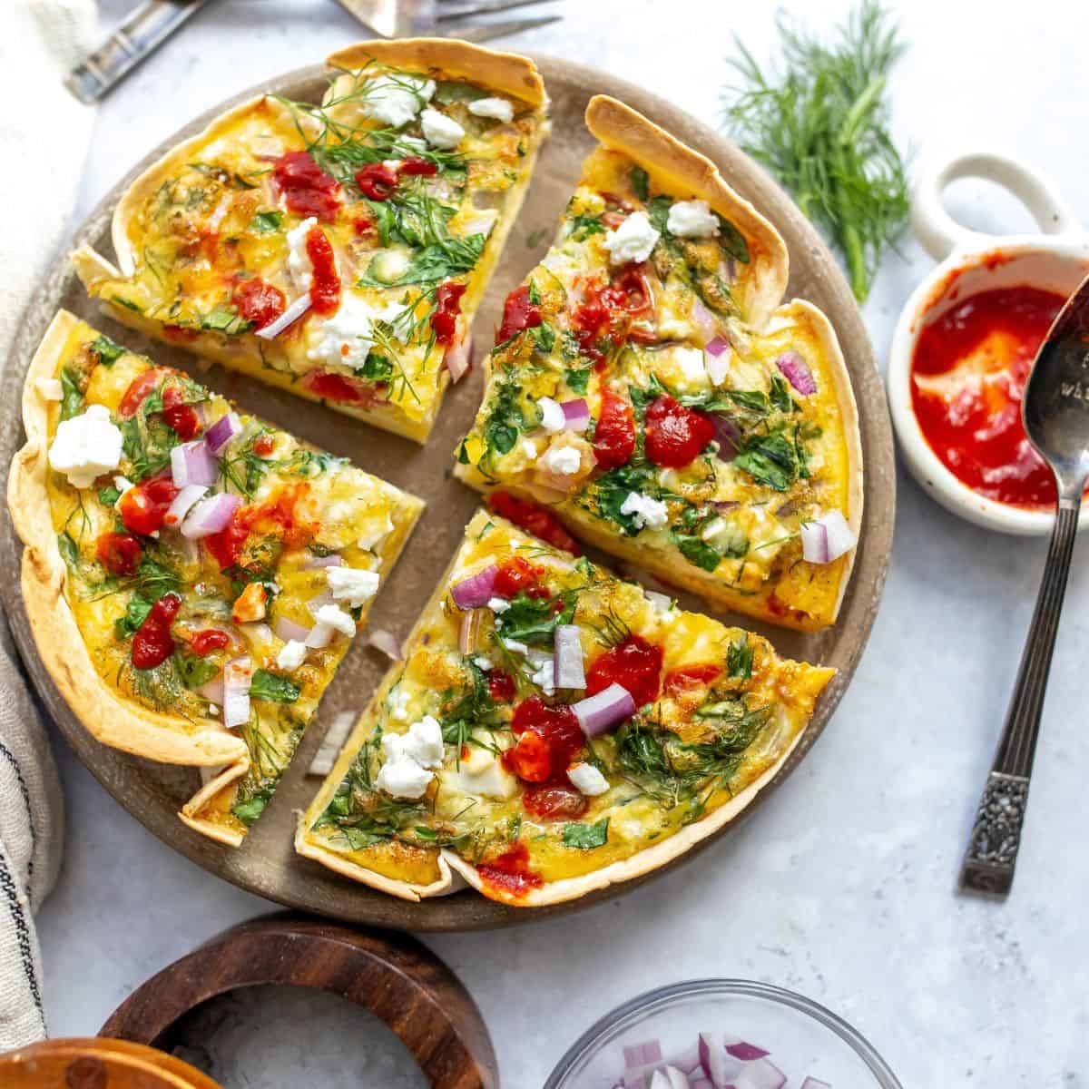 An overhead image of the tortilla quiche bake sliced in four on a serving plate.