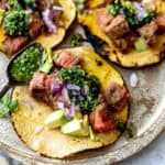 Steak tacos on a plate with chimichurri on them
