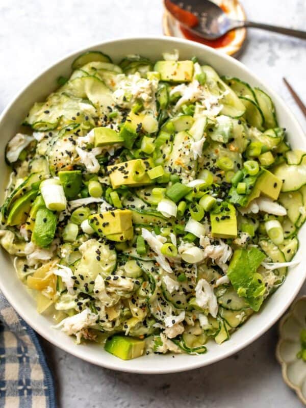 White bowl with filled with California Roll Cucumber Salad. Avocados on top with sesame seeds.