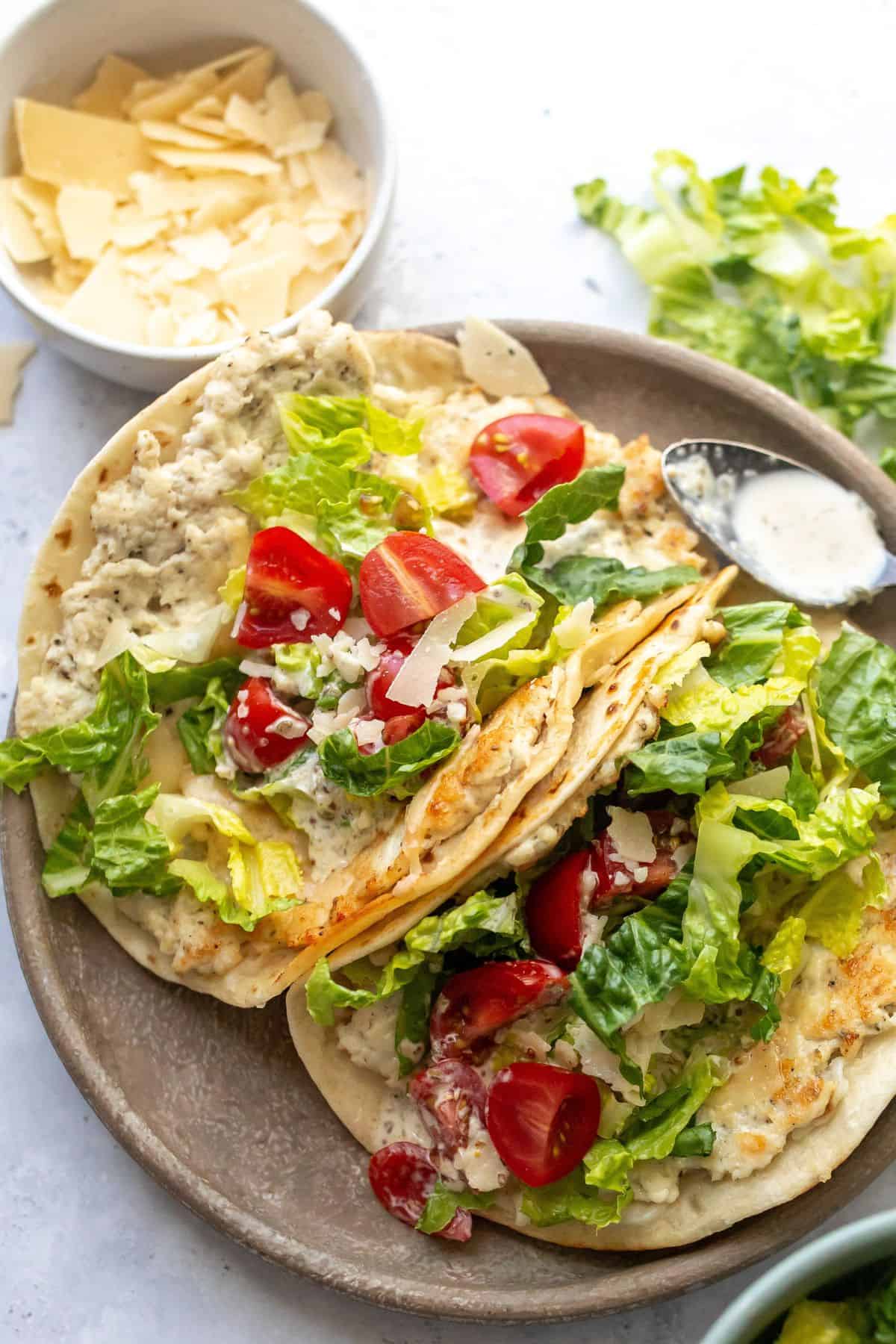 Chicken Caesar Smashed Tacos on a grey plate with dressing on the side and a spoon up close. 