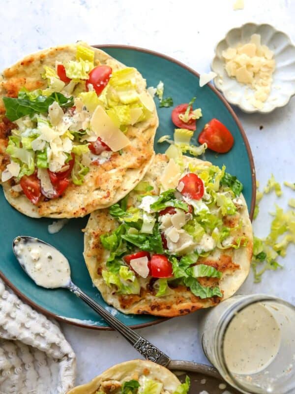 Chicken Caesar Smashed Tacos on a green plate with dressing on the side and a spoon.