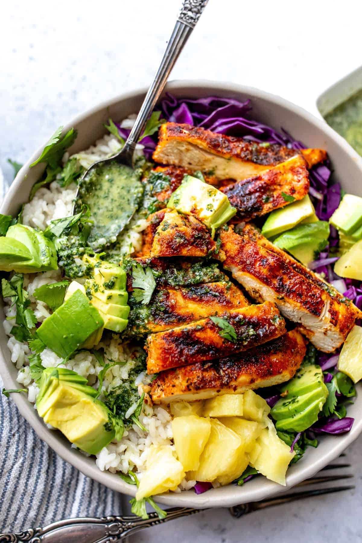 Bowl with blackened chicken and sauce on top with avocado.