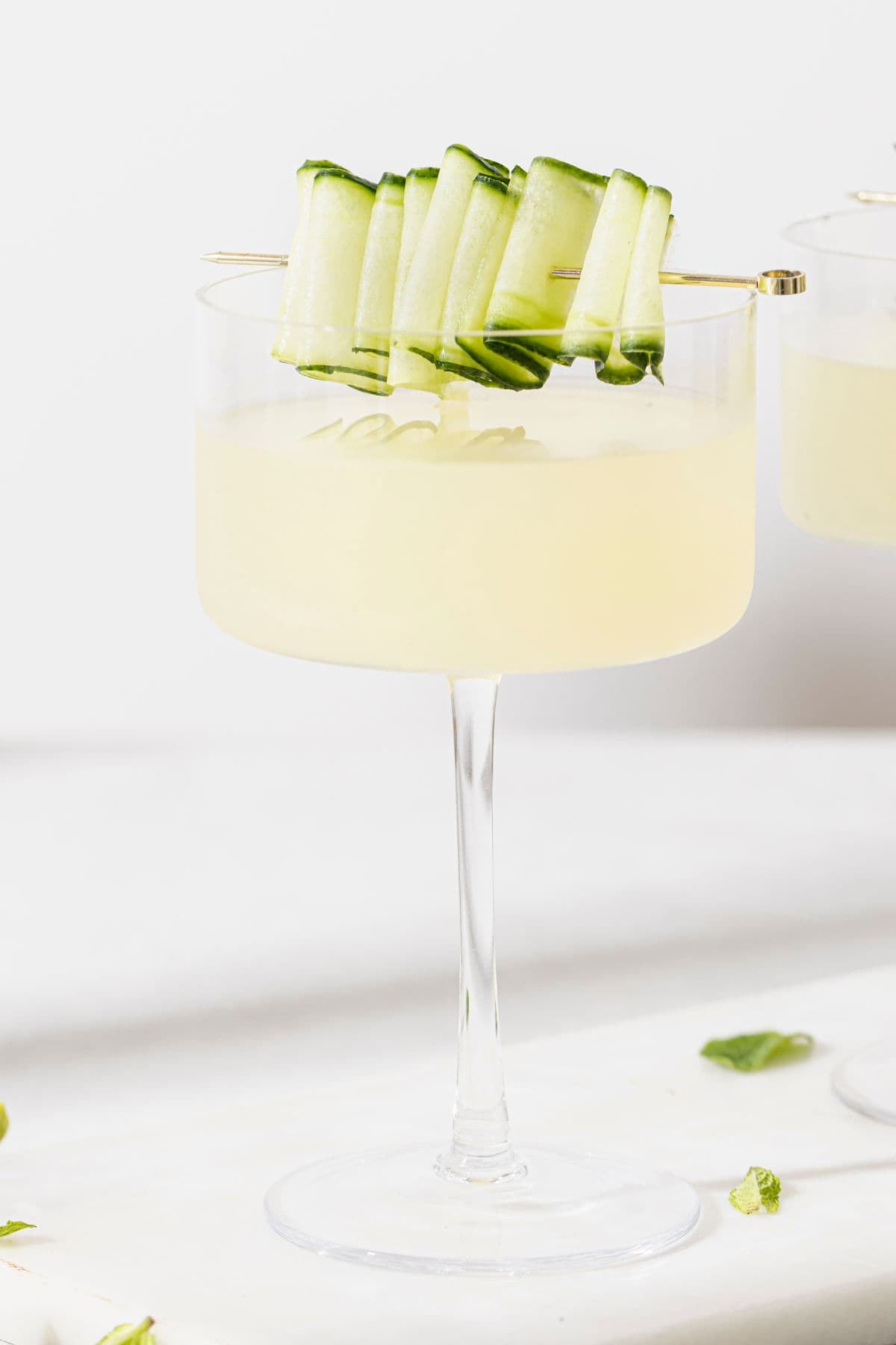 Refreshing Cucumber Martini in a glass with a cucumber ribbon garnished on top. 