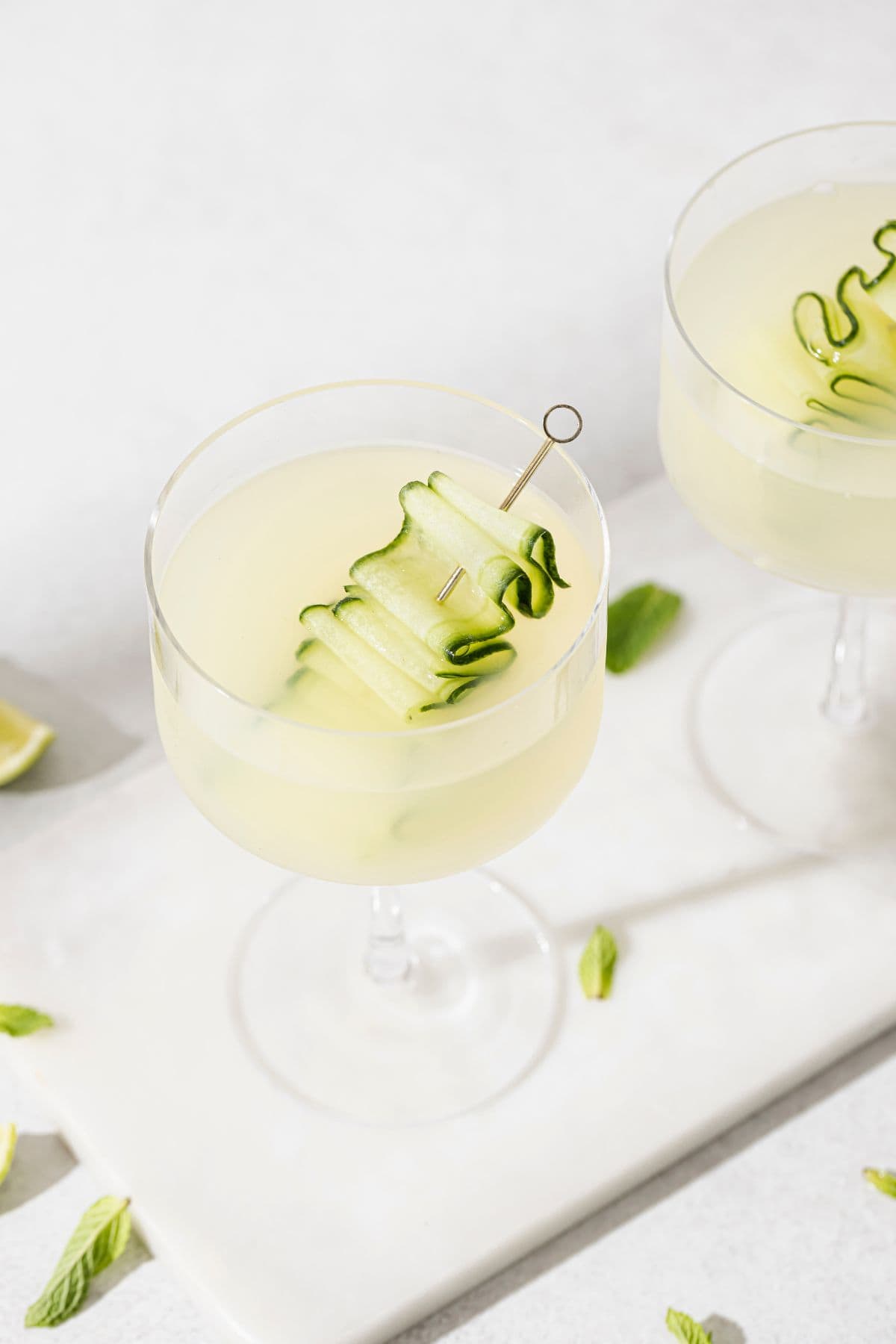 Chilled cucumber martini served in a stemmed glass, garnished with a ribbon of fresh cucumber on a cocktail pick.