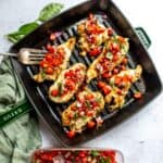 Grill pan with Grilled Caprese Chicken on it topped with tomatoes.