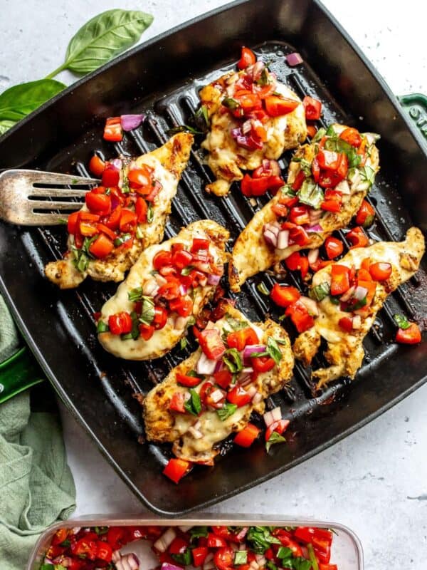 Grill pan with Grilled Caprese Chicken on it topped with tomatoes.