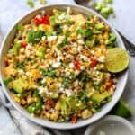 Mexican Street Corn Pasta Salad in a white ceramic bowl with a spicy lime on top.