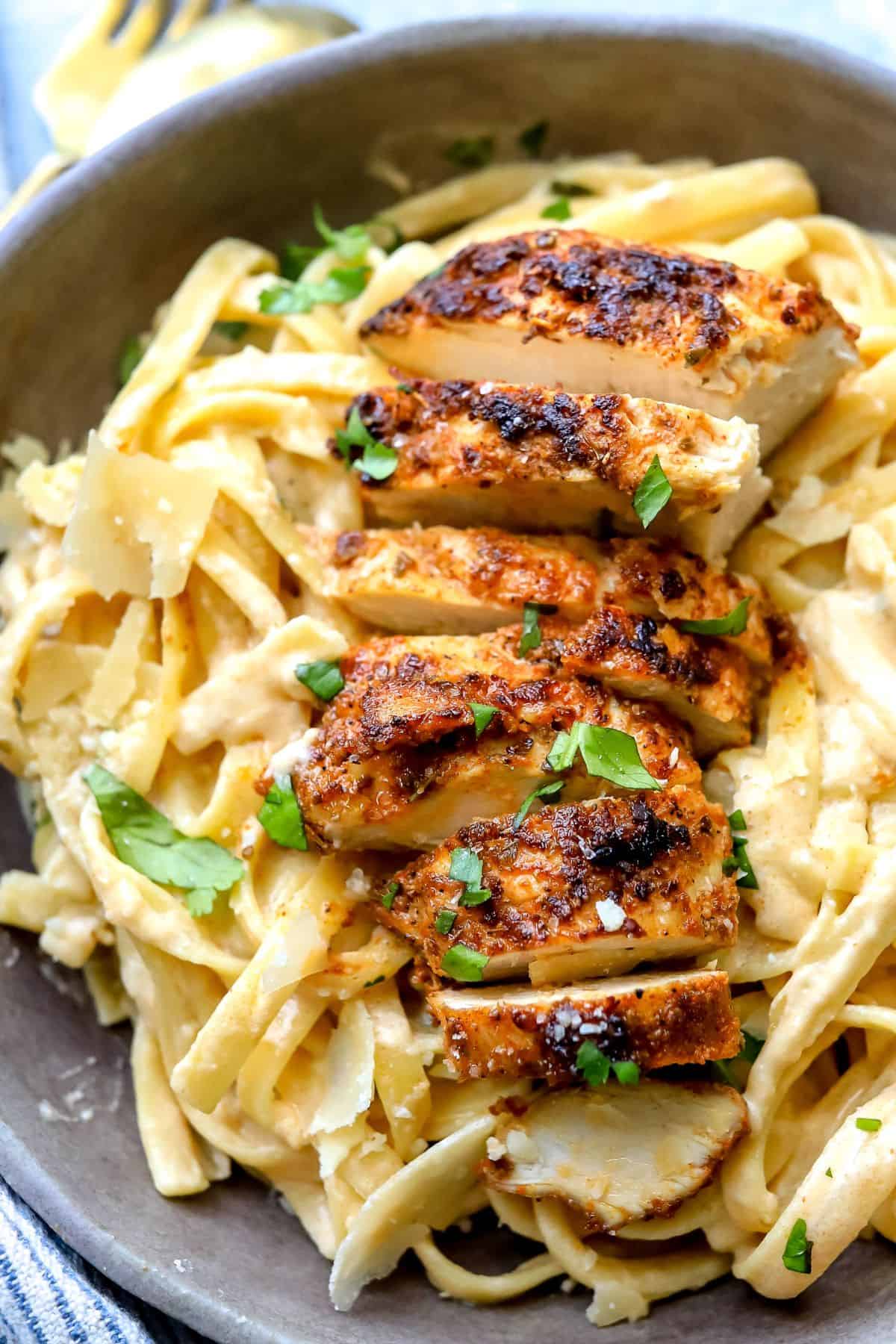 Up close photo of Blackened Chicken Fettuccine Alfredo in a grey bowl with sauce.
