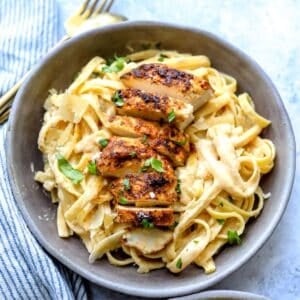 Grey ceramic bowl with Blackened Chicken Fettuccine Alfredo in it and fork to the side.