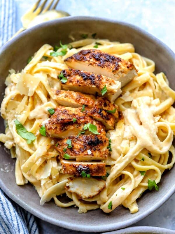 Grey ceramic bowl with Blackened Chicken Fettuccine Alfredo in it and fork to the side.