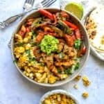 Grey bowl with Chicken fajita in it over rice with guacamole.