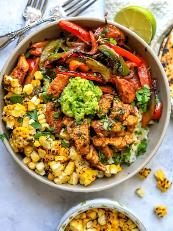 Grey bowl with Chicken fajita in it over rice with guacamole.