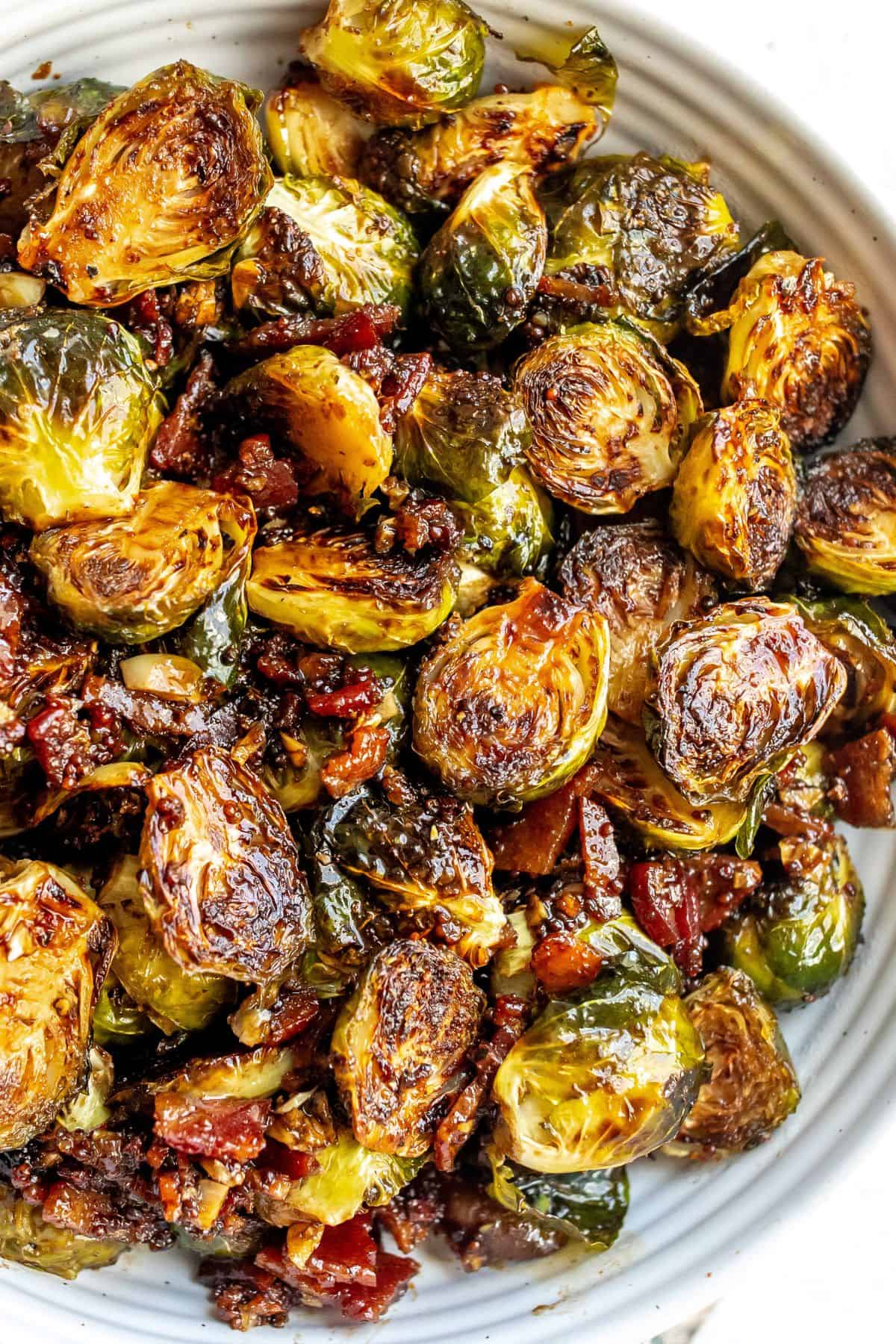 White bowl with Balsamic Honey Brussels Sprouts and honey on the side.