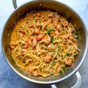 Stainless steal skillet with creamy Lobster Pasta in it and herbs.