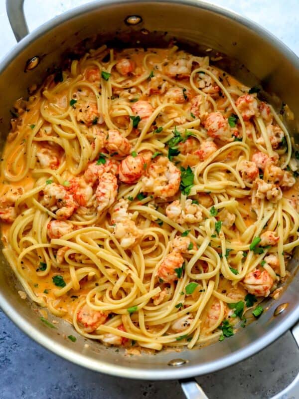 Stainless steal skillet with creamy Lobster Pasta in it and herbs.