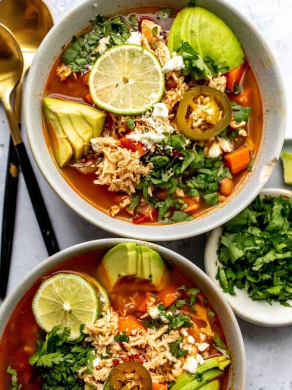 Mexican Chicken Lime Soup in two ceramic bowls with avocado and lime.