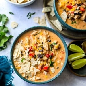 Green bowls with creamy taco soup in them and limes on the side.