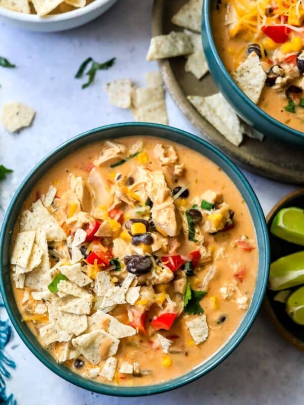 Green bowls with creamy taco soup in them and limes on the side.
