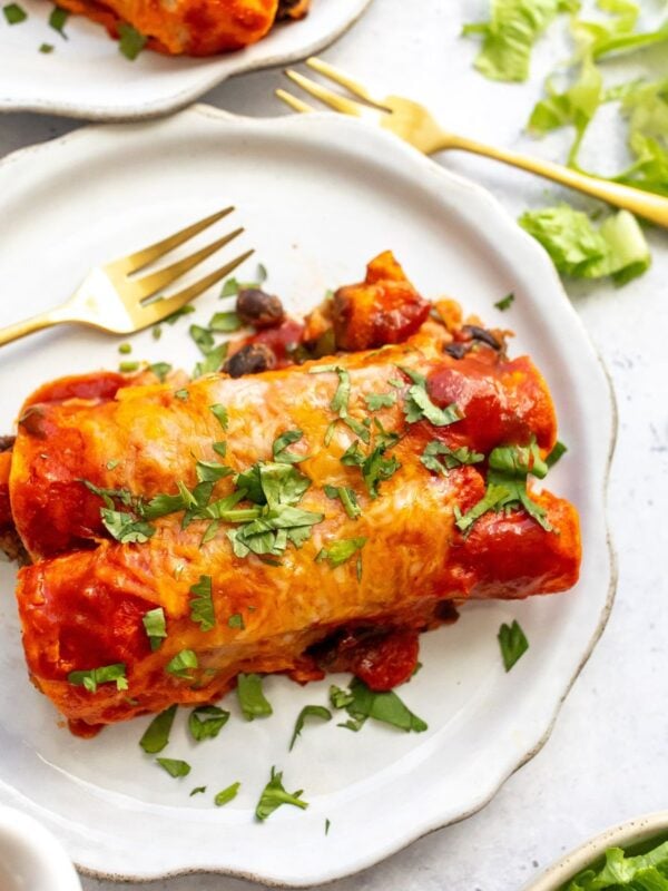 Vegetarian enchiladas on a plate with a gold fork.