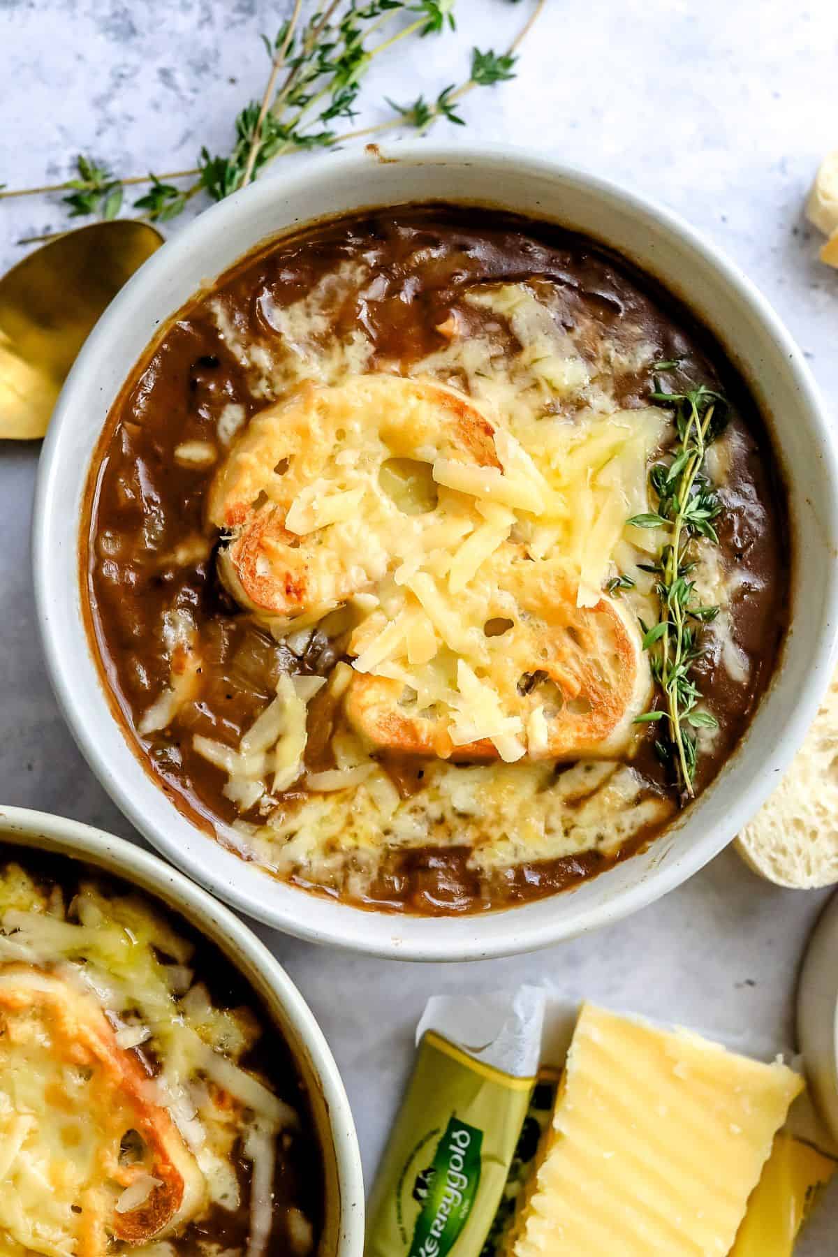Ceramic serving bowl with Healthy French Onion Soup and toasted baguette and melted cheese on top. 