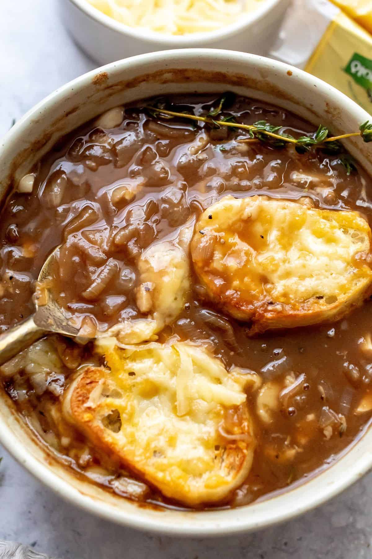 Healthy French Onion Soup in a bowl up close with a baguette and melted cheese.