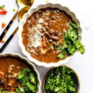 White ceramic bowl with Panera Black Bean Soup Recipe in the bowl with two spoons to the side.
