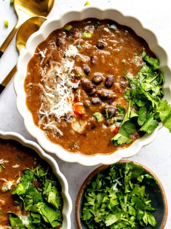 White ceramic bowl with Panera Black Bean Soup Recipe in the bowl with two spoons to the side.