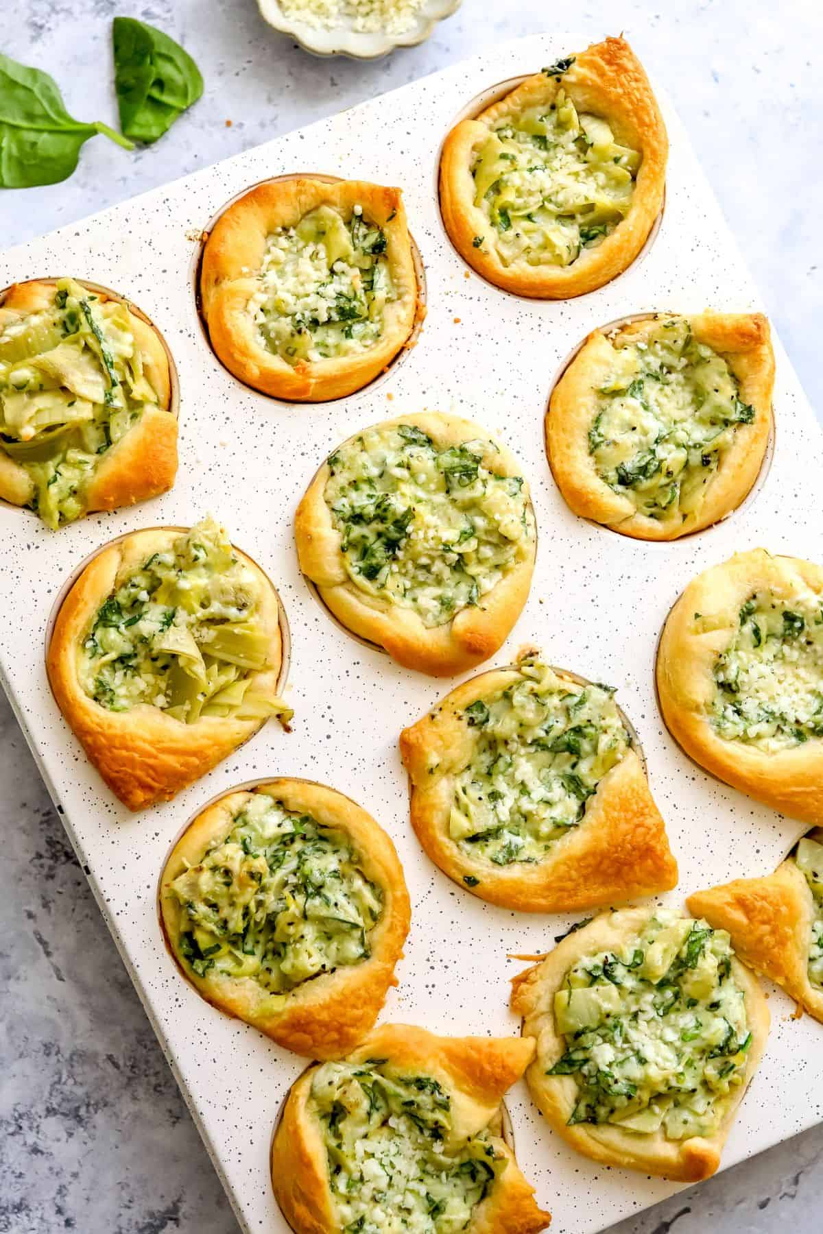 Muffin tin with Spinach Artichoke Dip Bites baked into it.