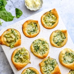 White muffin tine with Spinach Artichoke Bites in it, up close photo of them baked.