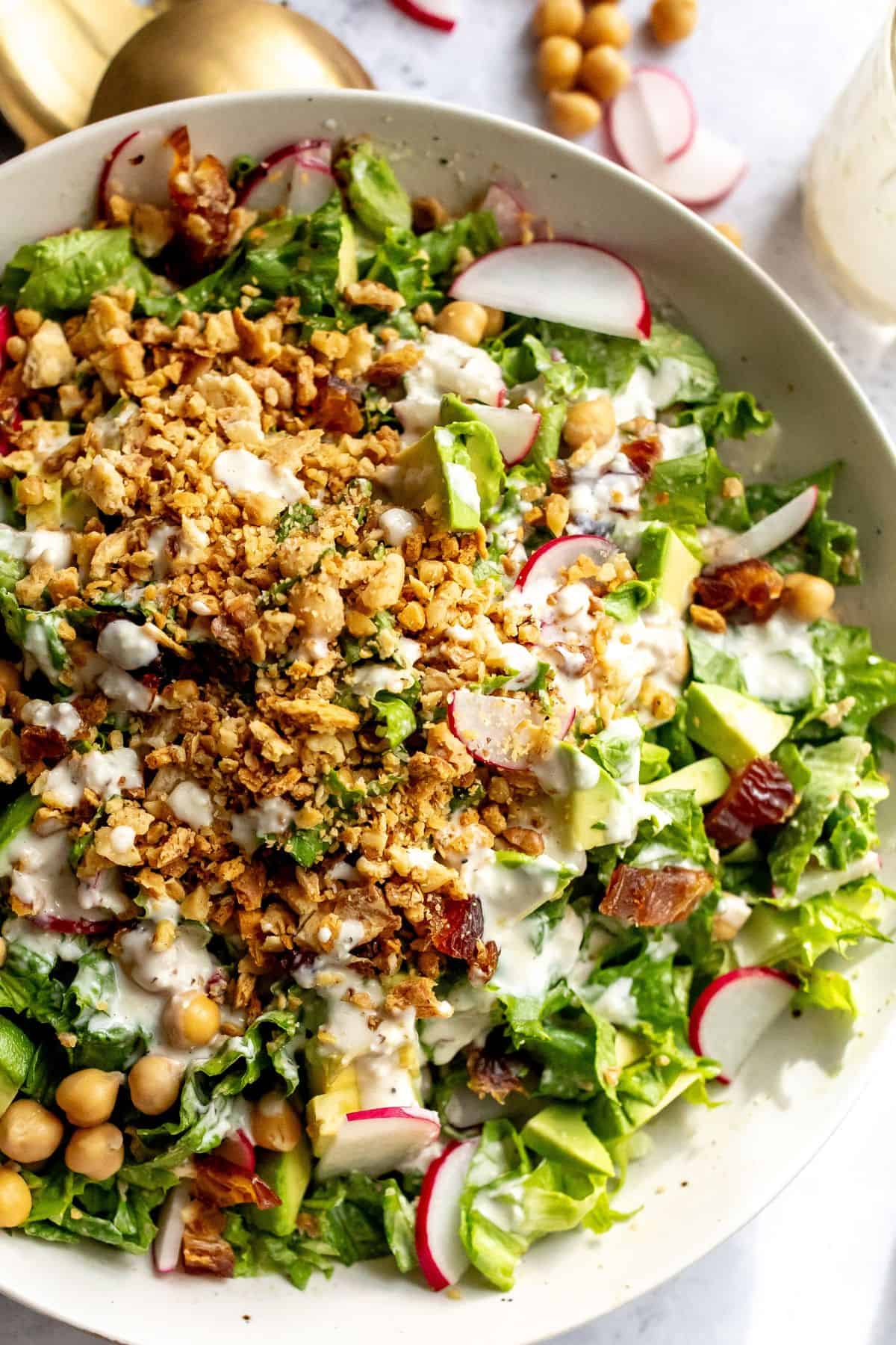 White ceramic bowl with Avocado Caesar Salad with lemon tahini salad dressing up close. 