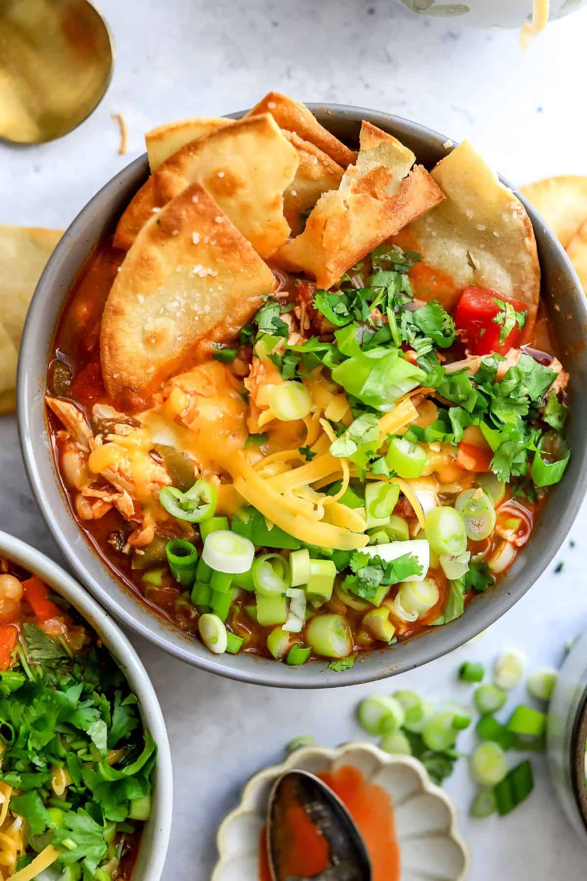 Grey ceramic bowl filled with buffalo chicken chili and topped with green onions.