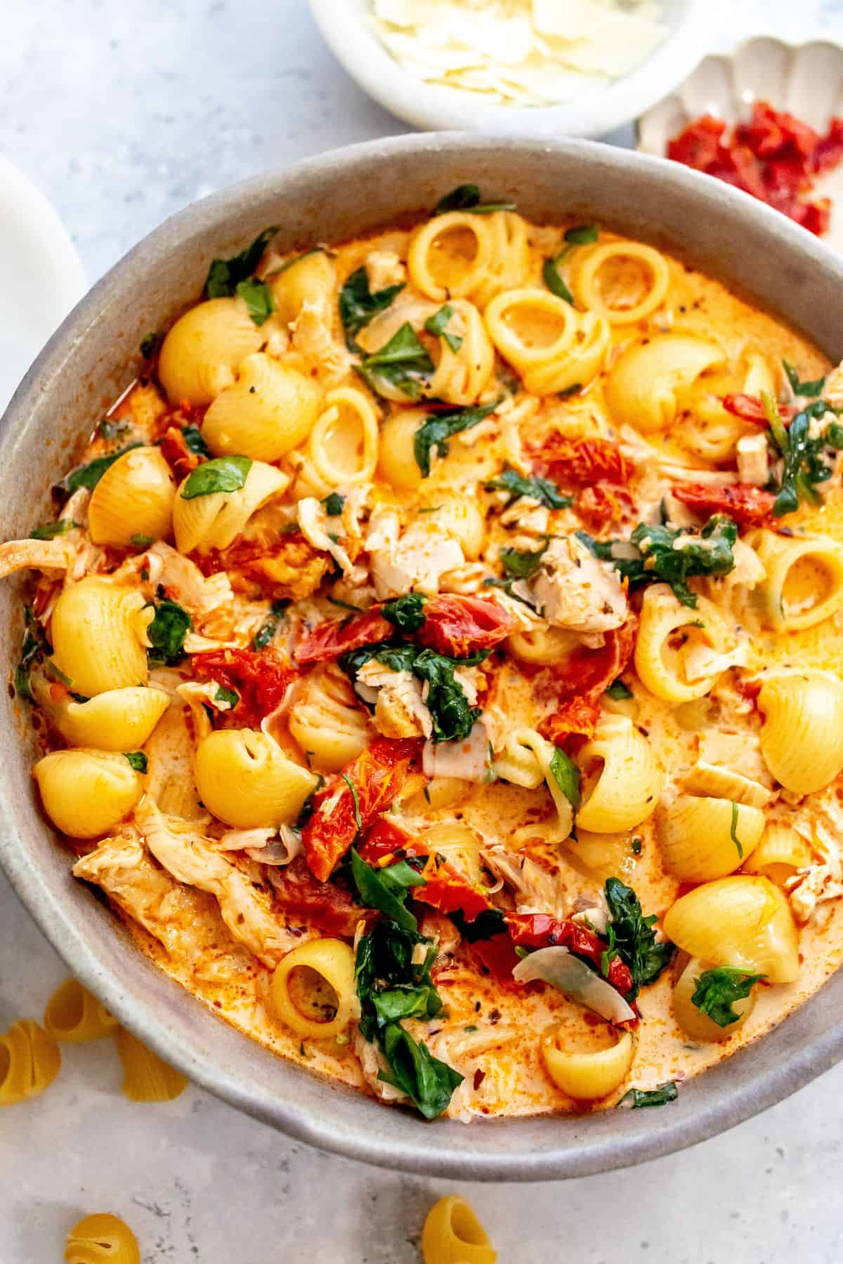 Grey bowl with Marry Me Chicken Soup in it and noodles off to the side.