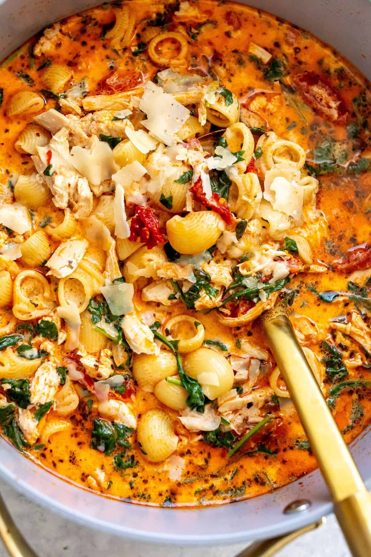 Large pot with marry me chicken soup and a golden ladle in it.