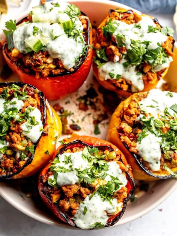 Ground turkey stuffed Peppers in a grey bowl with gold forks and plates on the side.