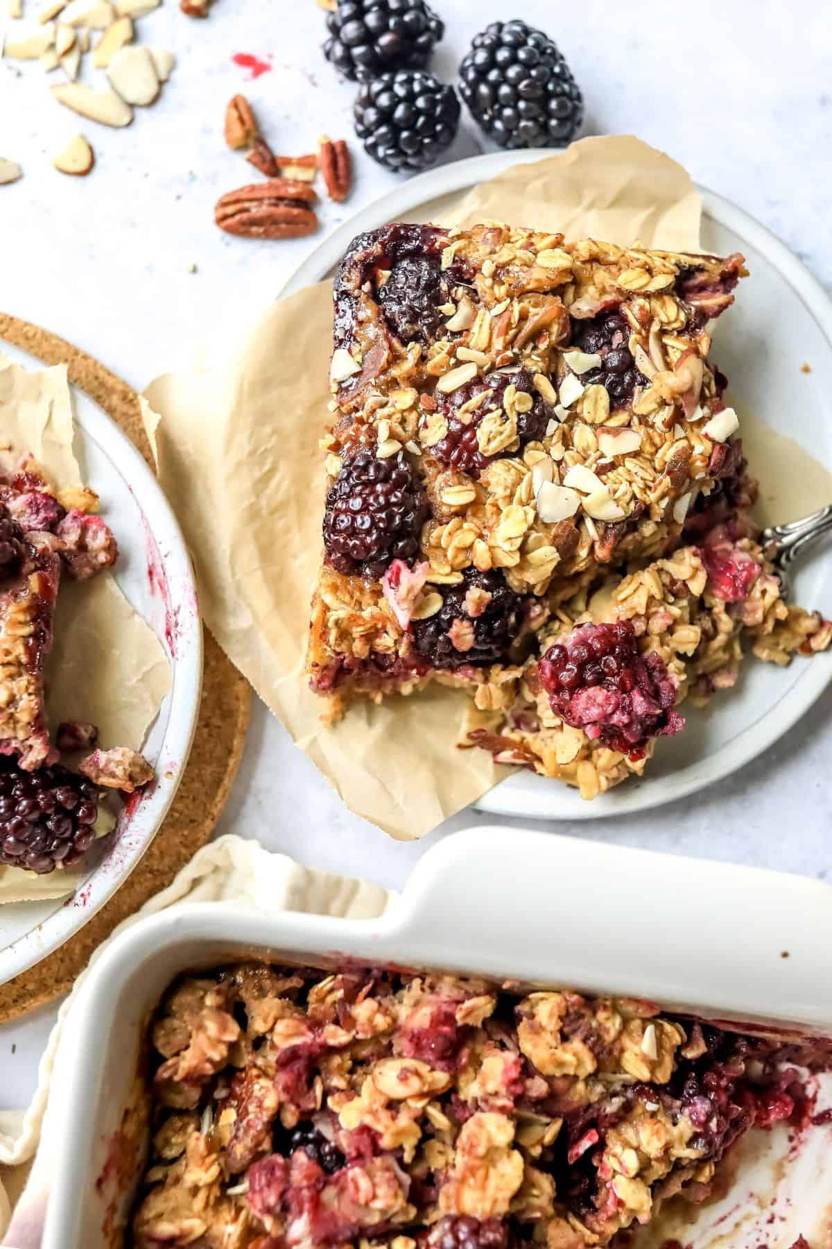 Blackberry Baked Oatmeal on a white plate with a fork on parchment paper.