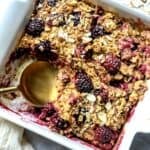 Blackberry Baked Oatmeal in a white baking dish with a spoon.