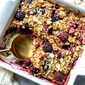 Blackberry Baked Oatmeal in a white baking dish with a spoon.