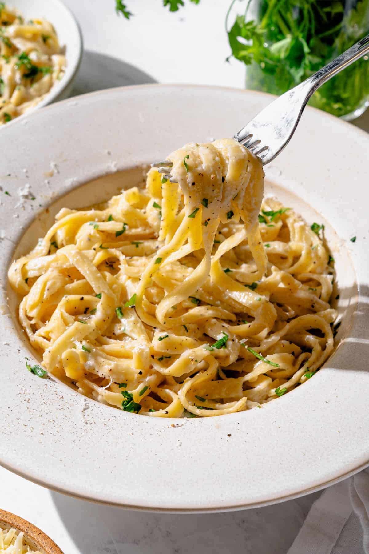 High Protein Cottage Cheese Alfredo Sauce in a white bowl with pasta on a fork.
