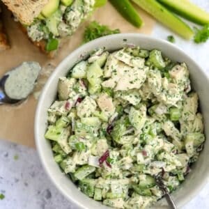 White ceramic bowl with Green Goddess Chicken Salad in it and dressing on the side with bread.