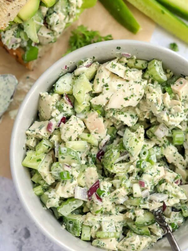 White ceramic bowl with Green Goddess Chicken Salad in it and dressing on the side with bread.