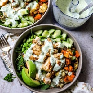 Grey bowls with chicken power bowls in them and dressed with sauce.