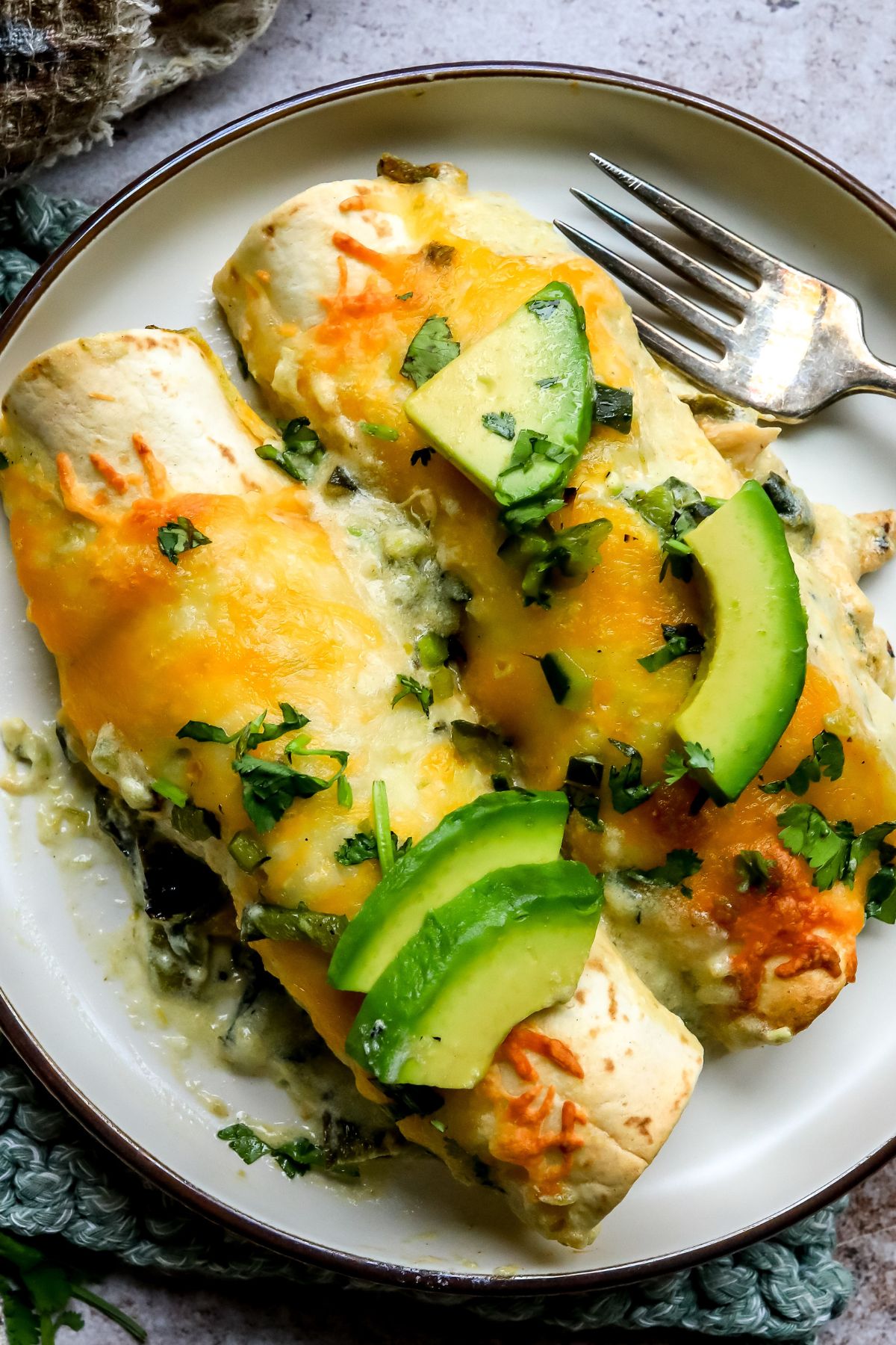 Poblano Chicken Enchiladas on a small plate with a silver fork to the side.
