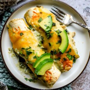 Poblano Chicken Enchiladas on a small plate with a silver fork to the side.