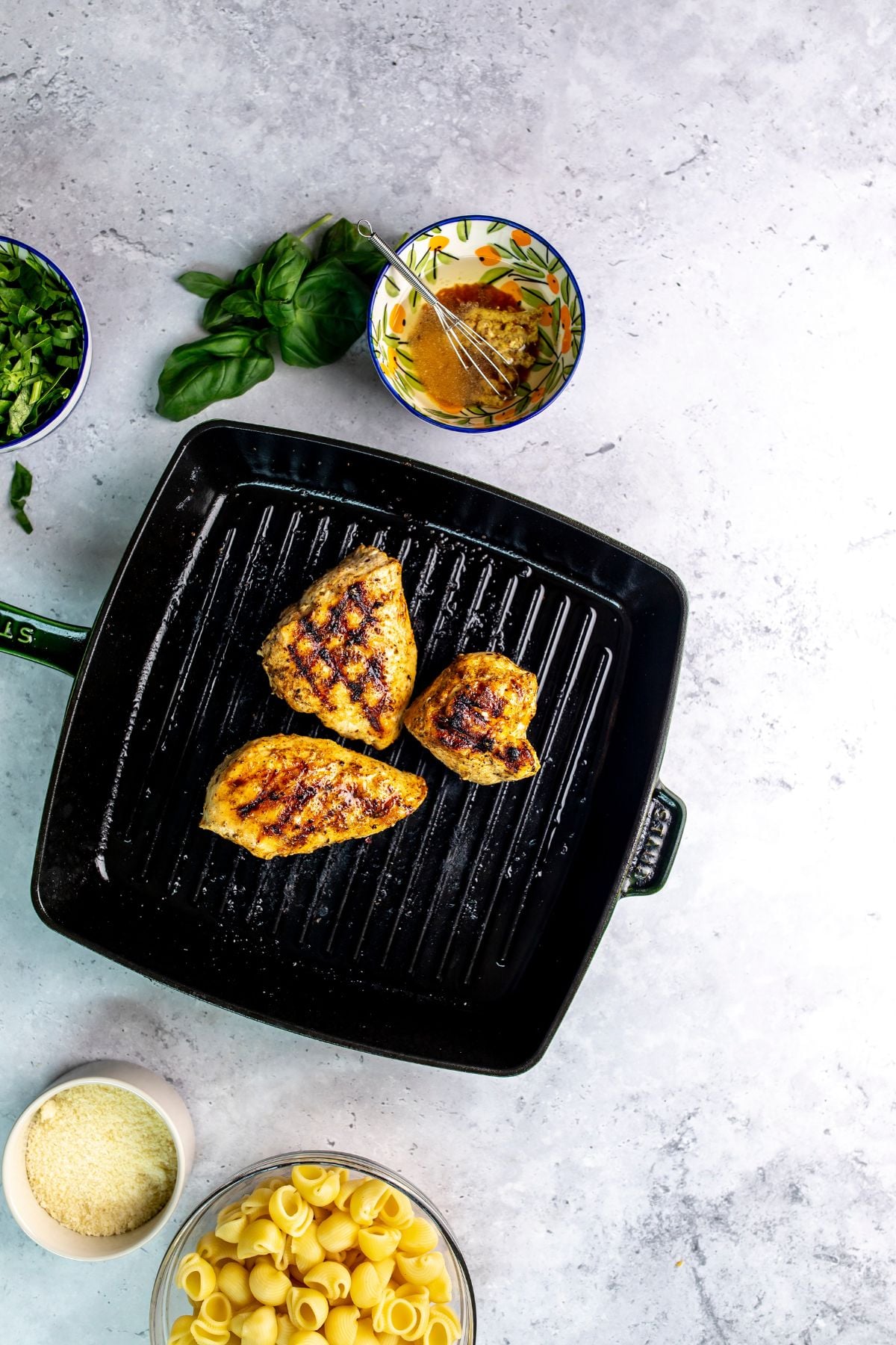 Dark green grill pan with chicken breasts on it cooking.