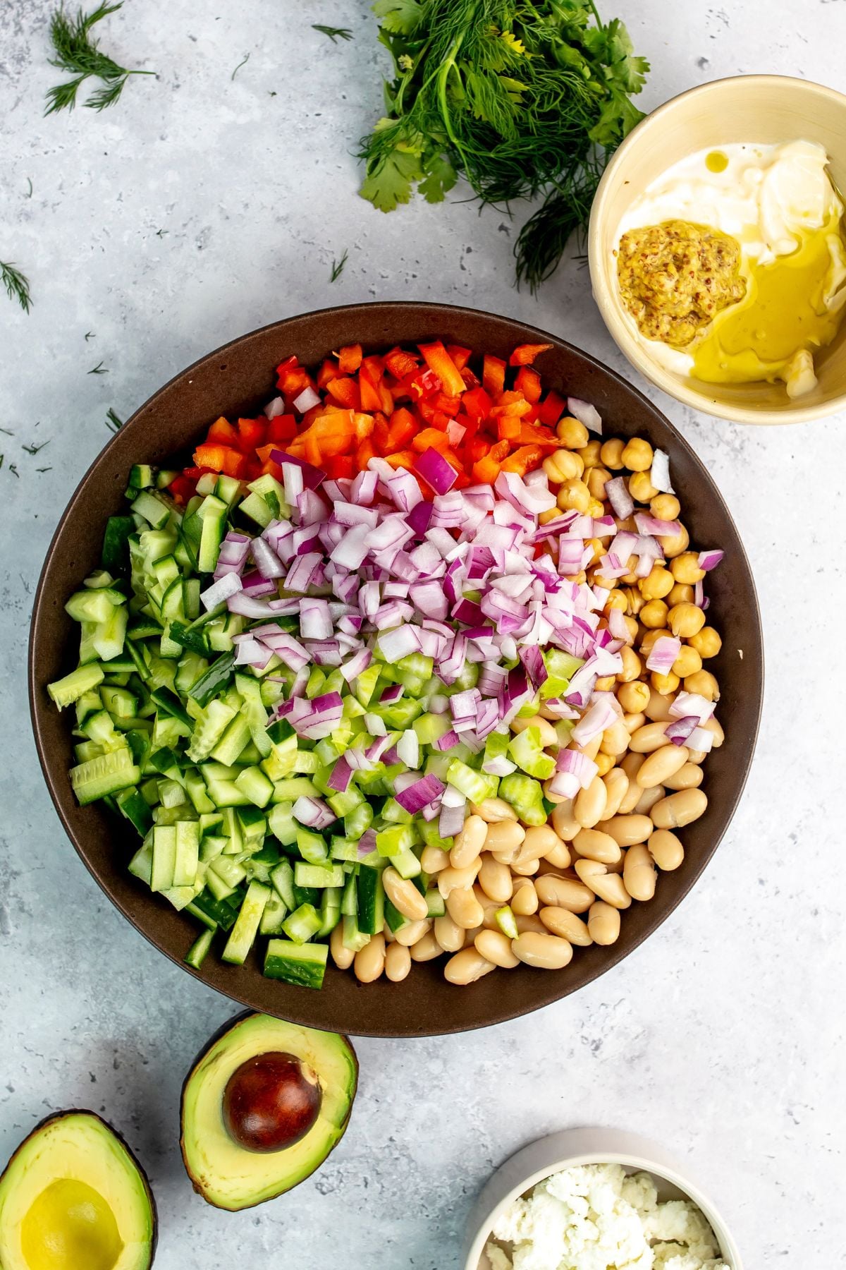 Brown bowl filled to the brim with fresh veggies and beans.