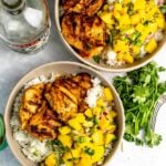 Tequila lime chicken served over rice and with mango salsa, tequila bottle on the side.